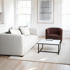 Modern living room with a gray sofa, brown armchair, and white coffee table.