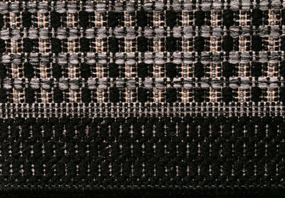 Close-up of a textured fabric with a checkered pattern in black, gray, and beige.