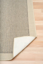 Textured rug with a white border on a wooden floor