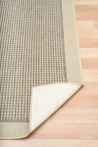 Textured rug with a white border on a wooden floor