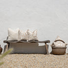 Wooden bench with decorative pillows against a light gray wall.