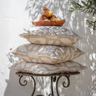 Stack of decorative pillows on a metal stand with a white wall and plant shadows in the background