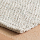 Close-up of a textured beige rug on a wooden floor