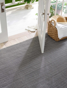 Gray patterned outdoor rug on a patio with a white door and basket in the background.