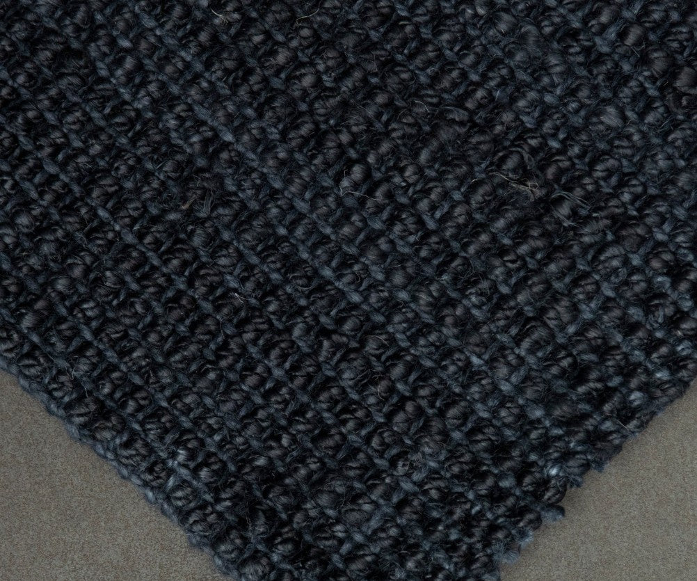 Close-up of a textured dark blue rug on a neutral background