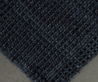 Close-up of a textured dark blue rug on a neutral background