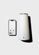 White humidifier with smartphone displaying humidifier app on a light gray background