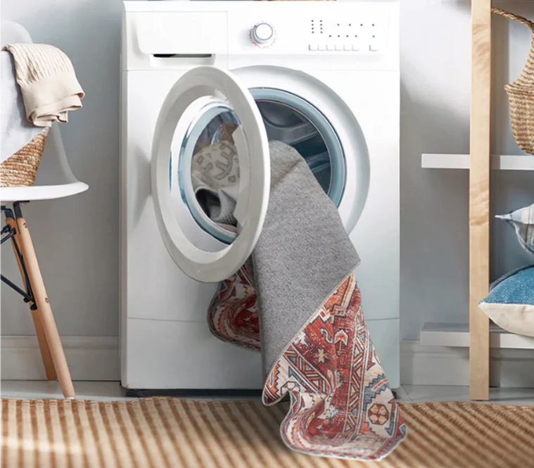 Washing machine with clothes draped over it in a laundry room.