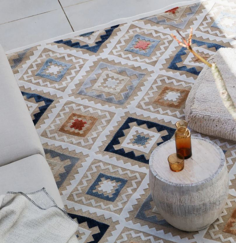 Patterned rug with a small table and candle on a light-colored floor