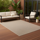 Outdoor patio with beige sofa, chair, and rug on a wooden deck.