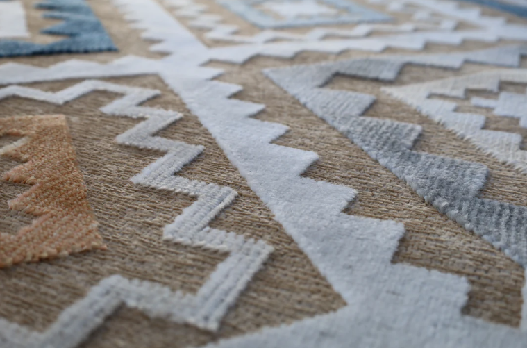 Close-up of a patterned rug with geometric designs in neutral colors.