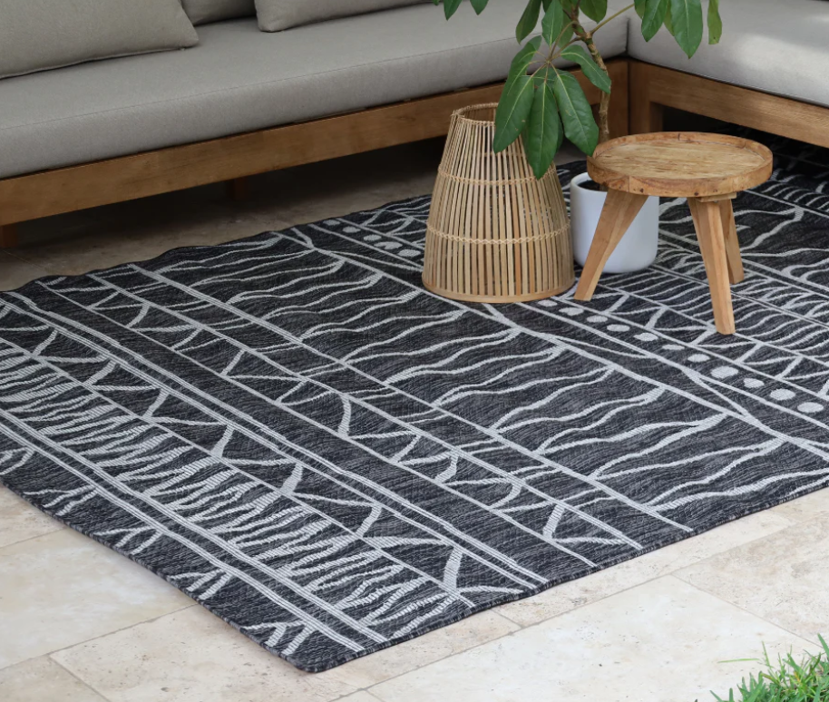 Patterned rug on a patio with outdoor furniture and plants.