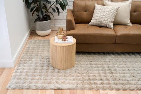 Living room with a brown sofa, wooden side table, and patterned rug.