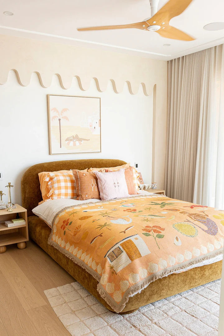 Bedroom with a bed covered in a colorful blanket and pillows, near a window with curtains.
