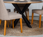 Dining table with black metal legs and wooden chairs on a textured rug.