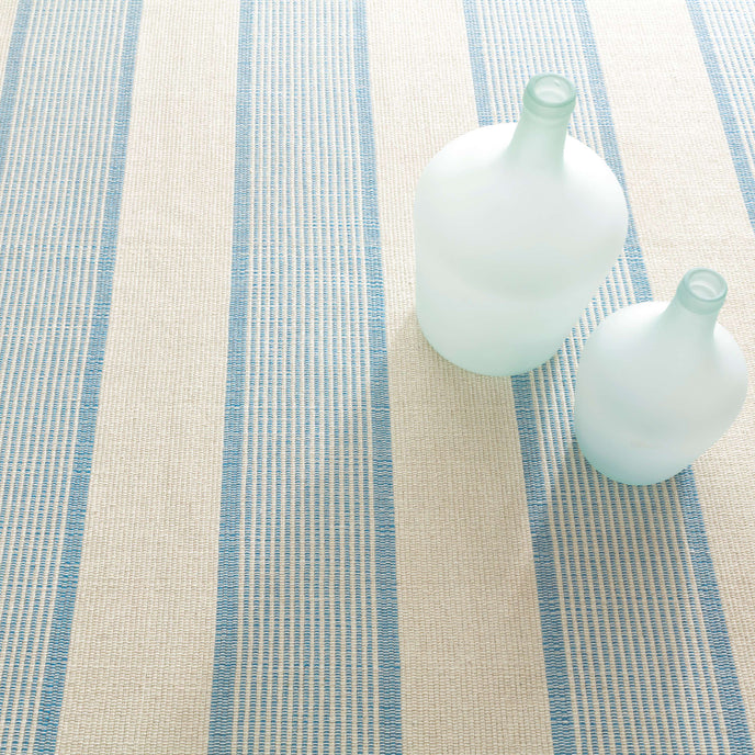 Two white bottles on a textured surface with blue stripes