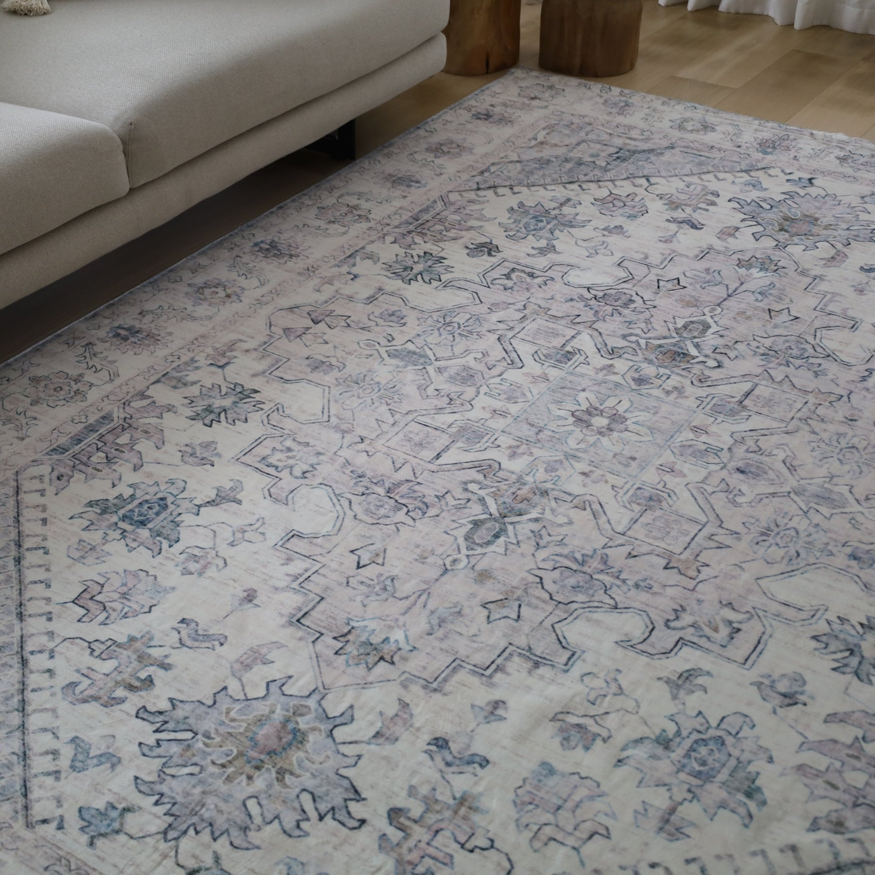 Patterned rug on a wooden floor with a beige sofa in the corner.