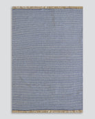 A rectangular woven rug with narrow horizontal navy and off-white stripes, finished with natural beige fringe on the top and bottom edges, shown against a neutral light gray background.