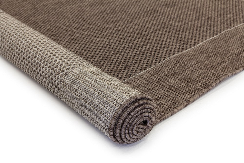 Image of the Outdoor Rug in Charcoal rolled up, revealing both the top surface and underside, demonstrating the rug's durability and craftsmanship.