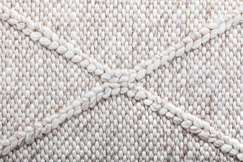 Close-up view of the Colombo beige rug highlighting the detailed braided diamond pattern and the rich, soft texture of the hand-woven New Zealand wool.