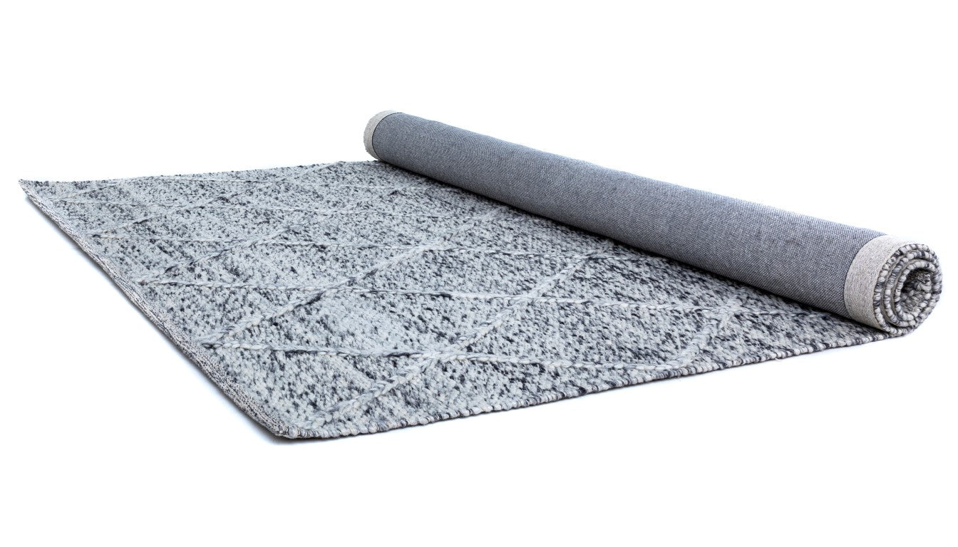 The Colombo Grey Rug neatly rolled up, displaying both the patterned top surface and the durable underside, illustrating the rug's craftsmanship and quality.