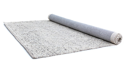The Colombo Light Grey Rug neatly rolled up, displaying both the patterned top side and the sturdy underside, illustrating the craftsmanship and durability of the rug.